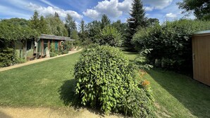 A well-maintained garden with a wooden structure, a clear path, and dense foliage. - Idyllische Ferienwohnung in Potsdam (Potsdam)