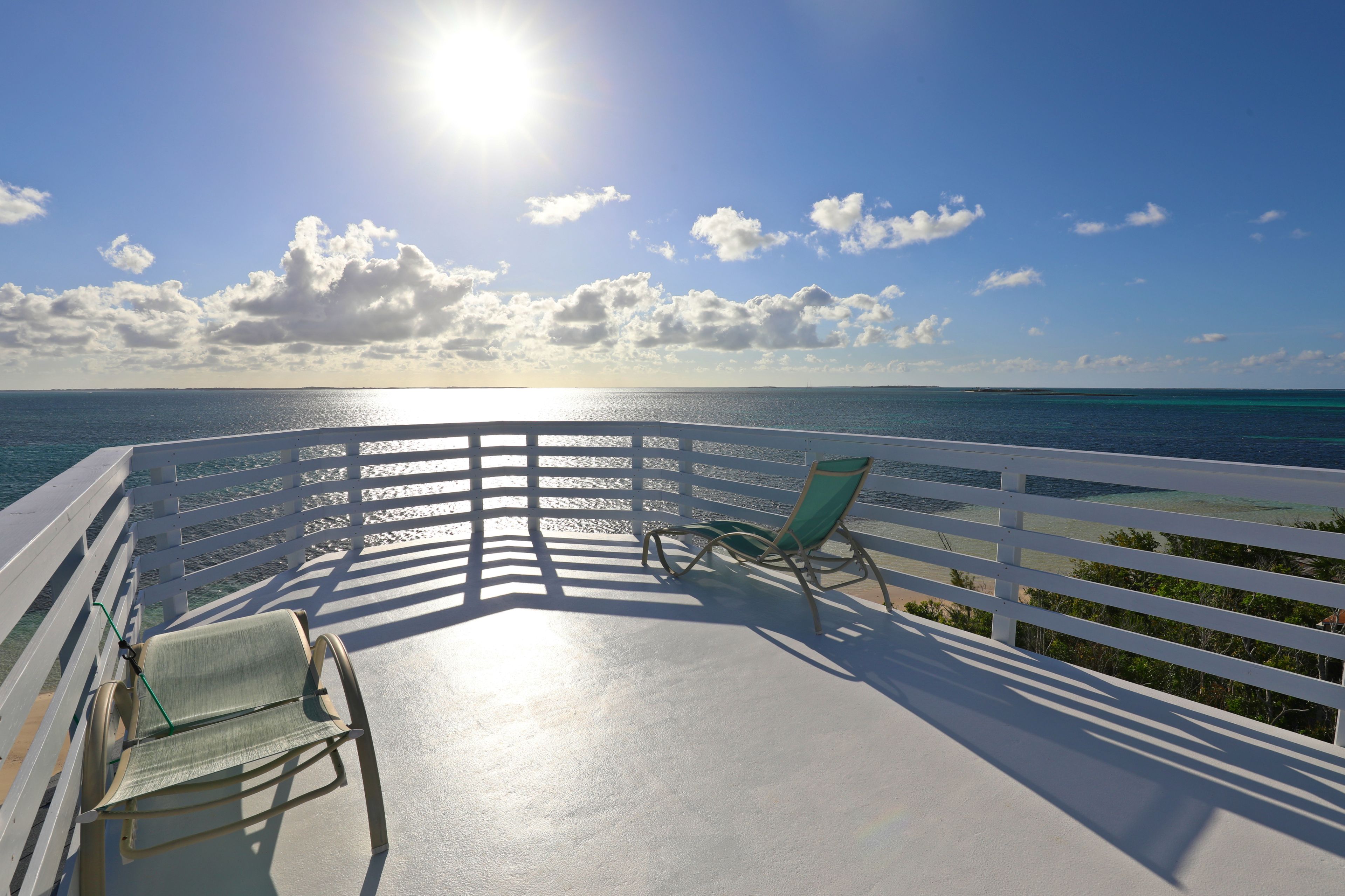 A balcony with a view of the ocean and a clear sky.