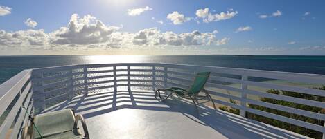 A balcony with a view of the ocean and a clear sky.