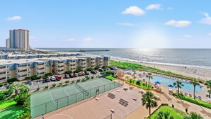 Un hôtel en bord de mer composé de plusieurs bâtiments, doté d’un court de tennis, d’un espace piscine et offrant une vue sur la plage.