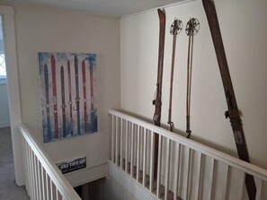 A staircase with a ski-themed wall art and ski equipment mounted on the wall. - Winnisquam Lakeside Funky Ski Chalet w-Sandy Beach & Boat Docks (Tilton)