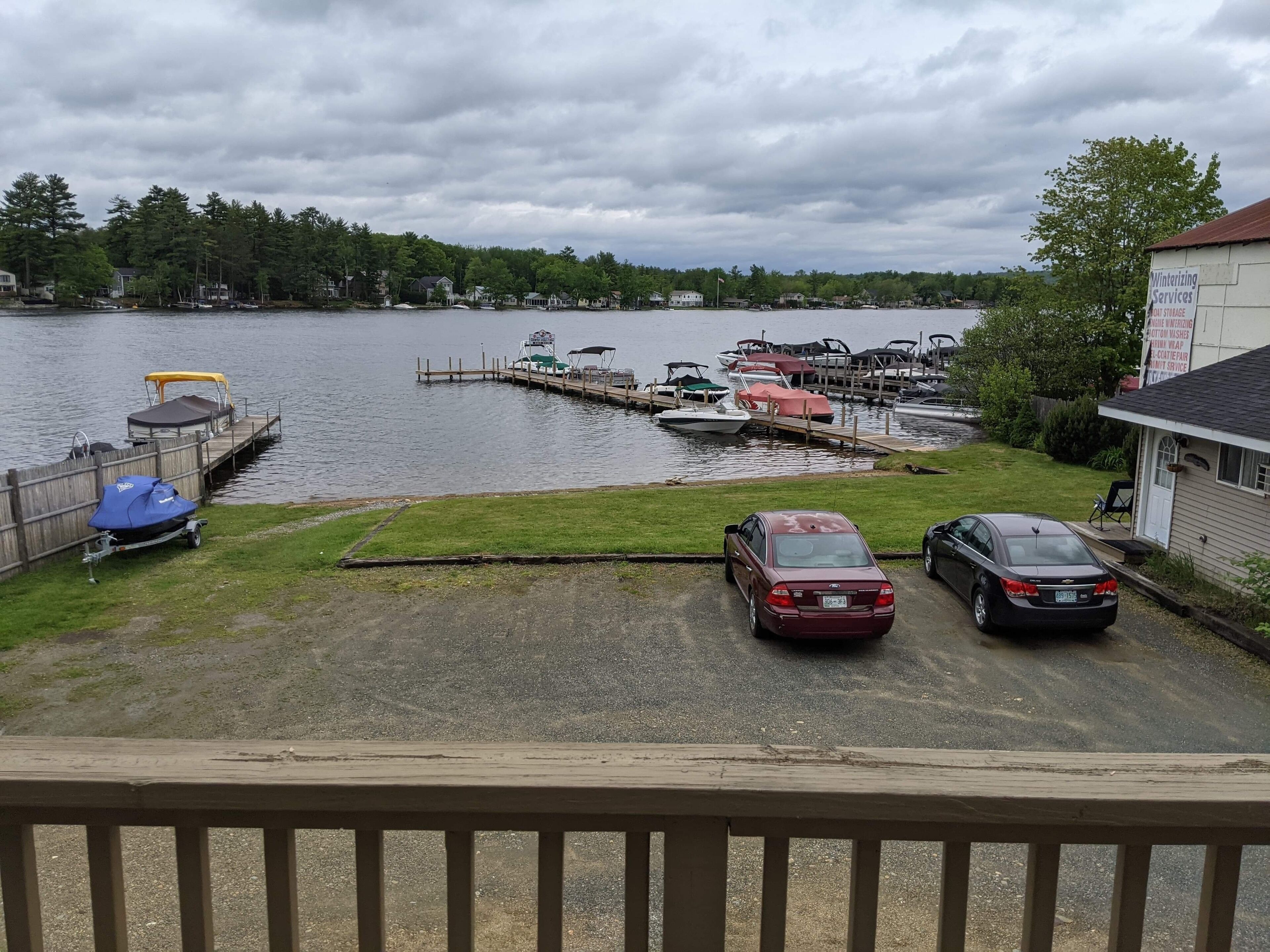 A marina with boats docked, a covered carport, and a grassy area with a wooden deck in the foreground.