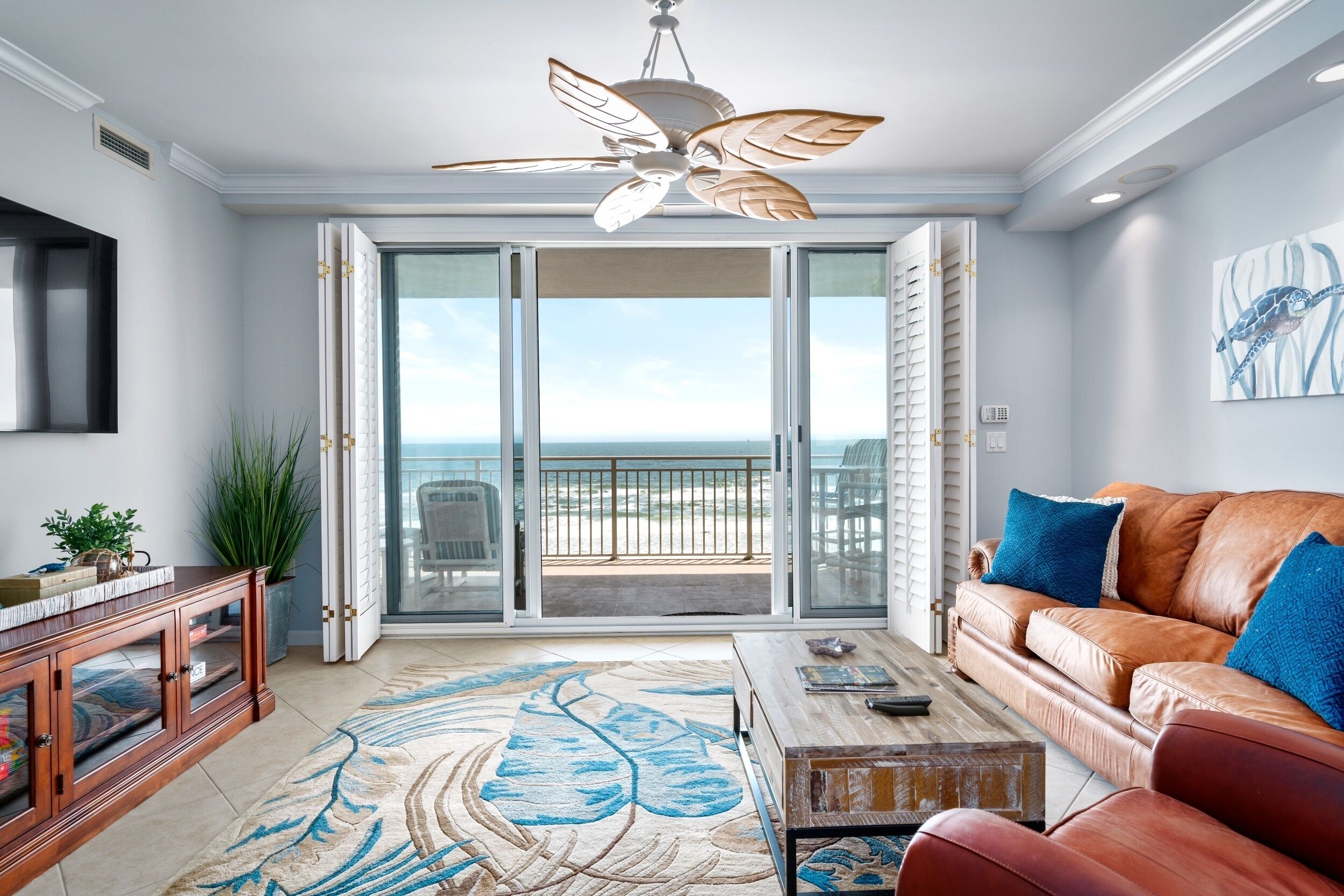 A living room with a leather sofa, a coffee table, and a large window with a view of the ocean.