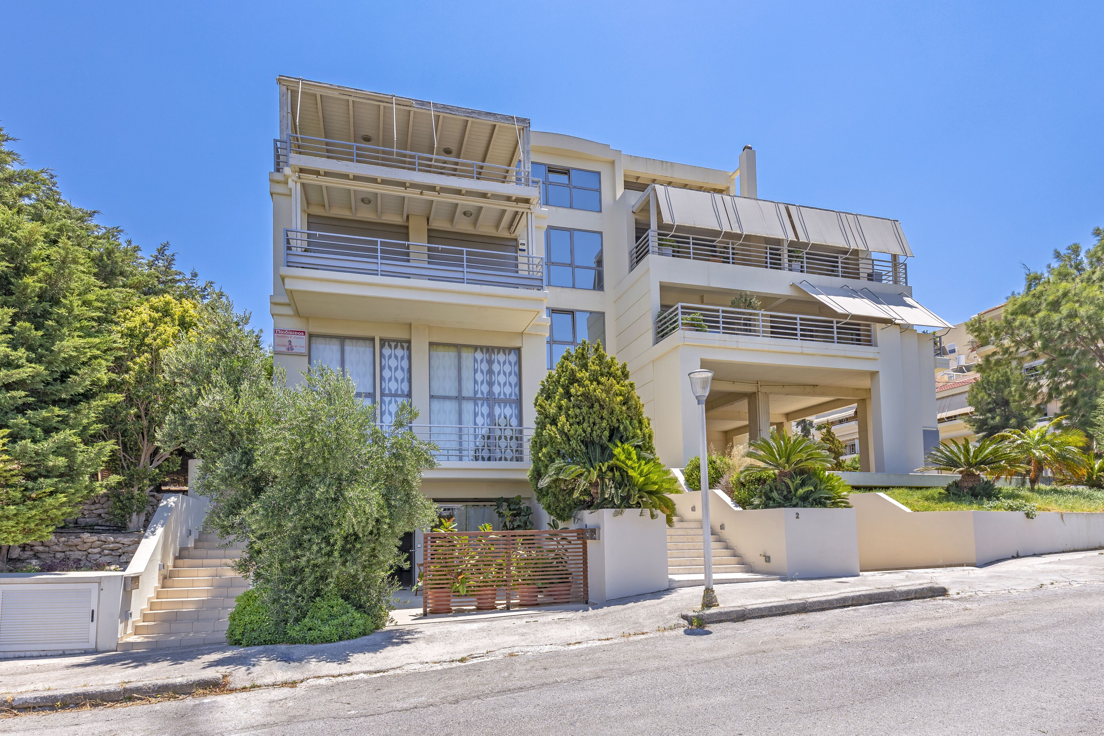 A multi-story residential building with balconies, a staircase, and a well-maintained garden.