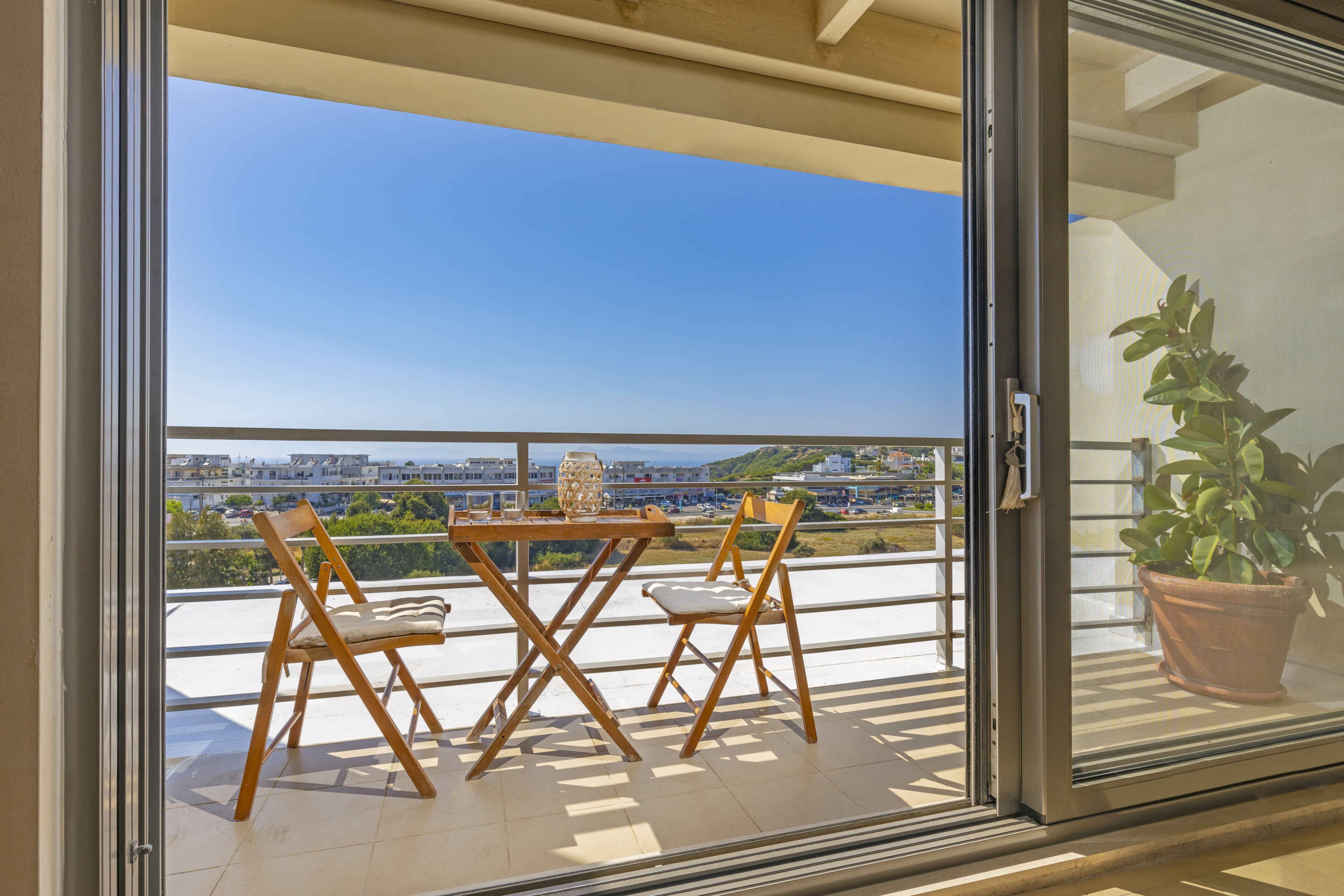 Ein Balkon mit Tisch, Stühlen, einem Blumentopf und Blick auf die Stadt.