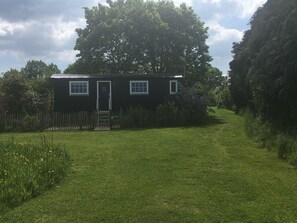 A small, single-story house with a front door, two windows, and a wooden fence. - SHEPHERD'S RETREAT (Alderholt)