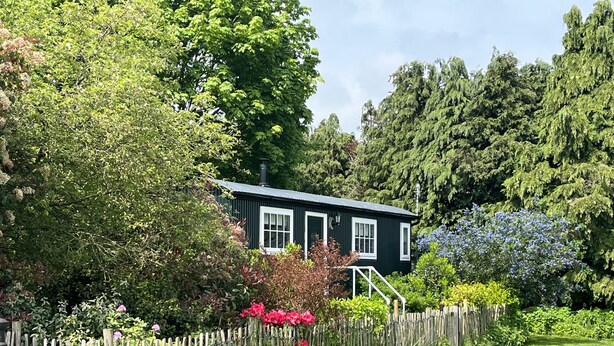Une maison à l’extérieur sombre, avec des fenêtres blanches et une clôture en bois.