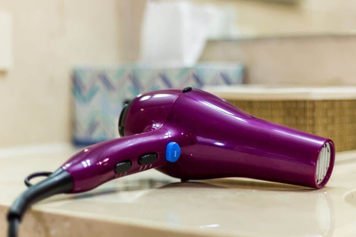 Un sèche-cheveux violet posé sur une surface en bois.