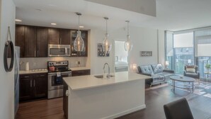 A modern kitchen with dark wood cabinets, stainless steel appliances, and pendant lighting. - 3380 Peachtree Rd NE Atlanta, GA 30326, USA (Atlanta)