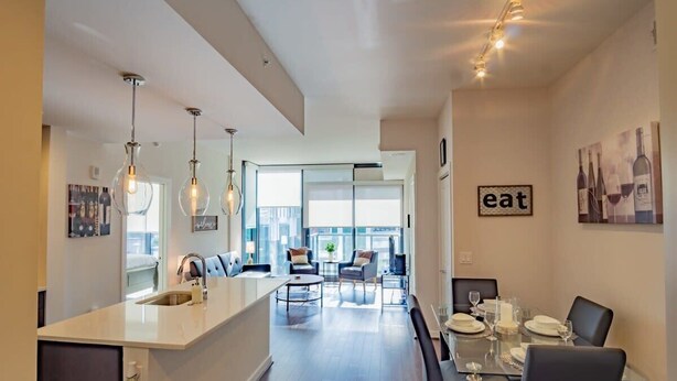 A modern kitchen with a central island, dining area with a glass table, and a living space with a sofa and chairs. - 3380 Peachtree Rd NE Atlanta, GA 30326, USA (Atlanta)