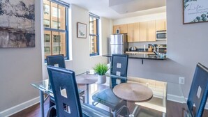 Een moderne keuken met roestvrijstalen apparatuur, een eethoek met glazen tafels en stoelen, en kunstwerken aan de wanden.