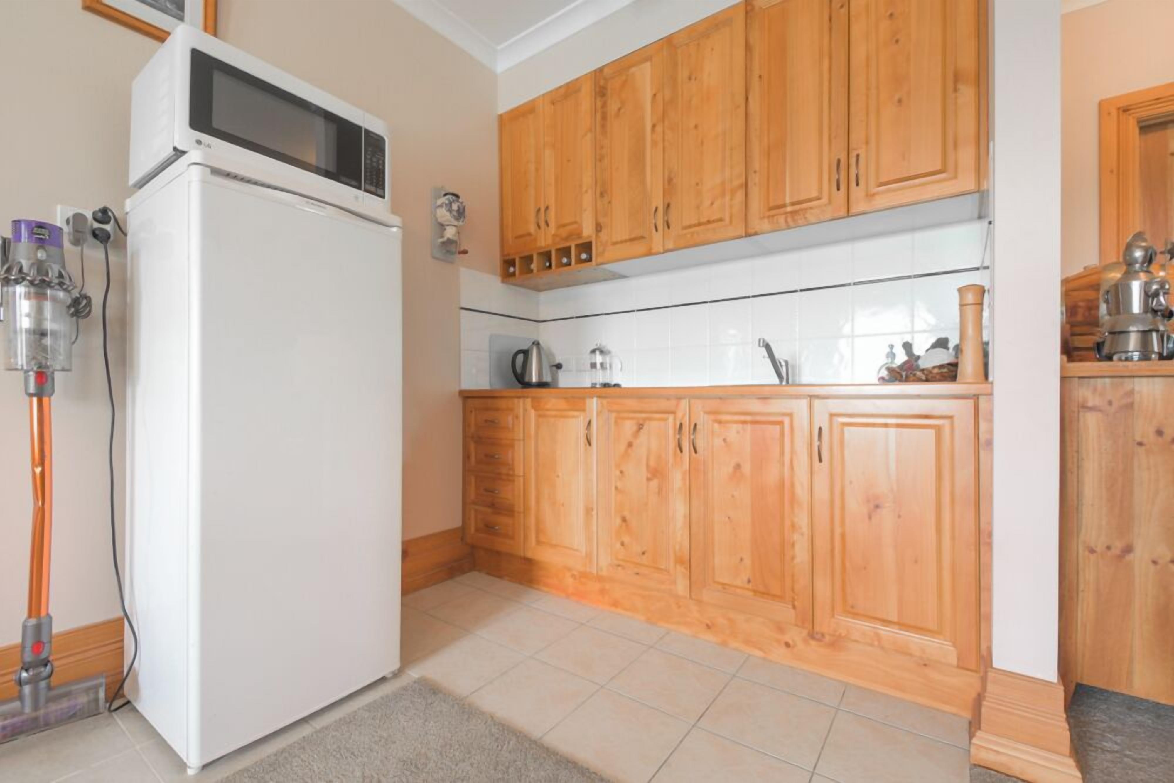 A kitchen with wooden cabinets, a white refrigerator, and a microwave.