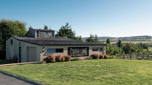 A building with a sign reading "Cobra Linn Distillery" surrounded by a grassy field and a wooden fence. - Rural Apartment with Stunning Views! (Relbia)