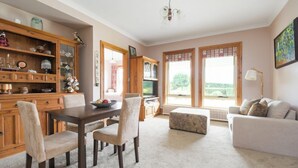 A spacious living room with a dining area, a sofa, and a television. - Rural Apartment with Stunning Views! (Relbia)