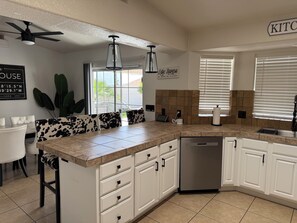 A modern kitchen with white cabinets, a granite countertop, and a built-in dishwasher.