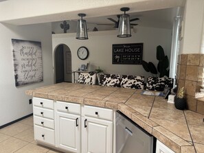 A kitchen with a large island, white cabinetry, a clock, and a sign indicating the establishment year.