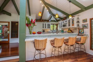 A kitchen with a bar area, wooden flooring, and a view of the outdoors.