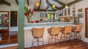 A kitchen with a bar area, wooden flooring, and a view of the outdoors. - Hanalei Happy Place, Incomparable Home TVNC#1158 (Hanalei)