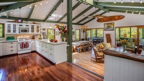 A spacious kitchen with white cabinets, a wooden island, and a dining area with wooden furniture. - Hanalei Happy Place, Incomparable Home TVNC#1158 (Hanalei)