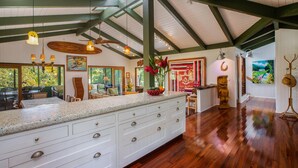 A spacious kitchen with a large island, wooden beams, and a view of the outdoors. - Hanalei Happy Place, Incomparable Home TVNC#1158 (Hanalei)