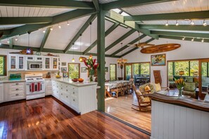 A spacious kitchen with white cabinets, a wooden island, and a dining area with wooden furniture.