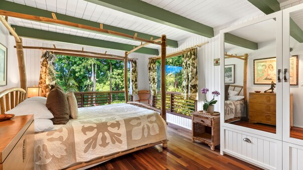 A bedroom with a four-poster bed, wooden flooring, and a balcony with a view of greenery. - Hanalei Happy Place, Incomparable Home TVNC#1158 (Hanalei)