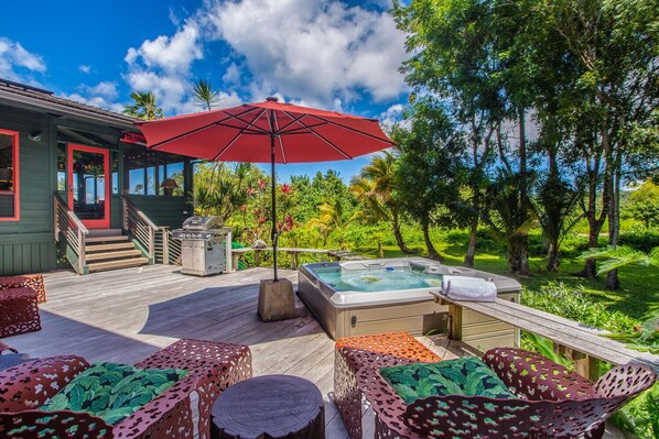 A deck with outdoor seating, a hot tub, and a grill.