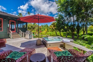 Relax on the deck with a hot tub, wicker chairs, and a round table.