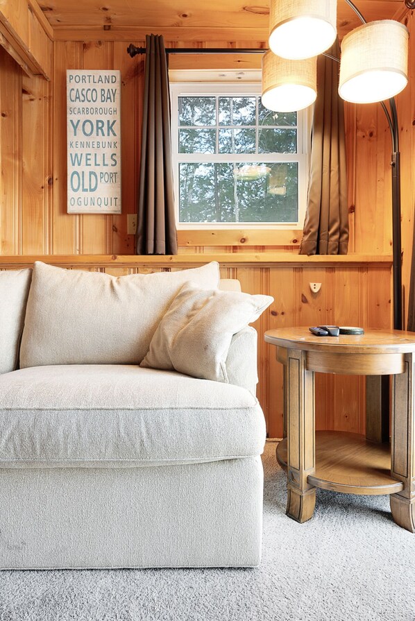 A cozy cabin interior with a wooden interior, a sofa, a table, and a sign listing various locations.