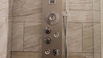 A modern shower with multiple controls and a handheld showerhead, set against a backdrop of marble tiles.