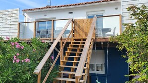 Une maison à deux étages avec un escalier en bois menant à un balcon.