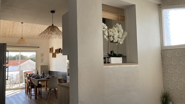 Une cuisine moderne avec des meubles en bois, un coin repas doté d’une table et de chaises en bois, et un luminaire suspendu.