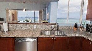 A kitchen with granite countertops, stainless steel appliances, and wooden cabinets. It features a large window with a view of the ocean. - $3,000,000 Luxury Beach Front (4) Bedrooms Condo famous West Bay Beach Sleeps 8 (West Bay)