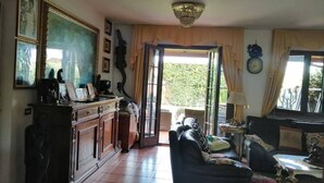 Un salon spacieux avec un canapé en cuir foncé, un meuble en bois et un lustre.