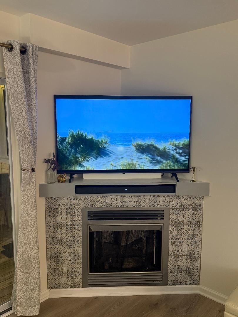 Un téléviseur à écran plat fixé au-dessus du manteau de cheminée, affichant une scène de paysage marin.
