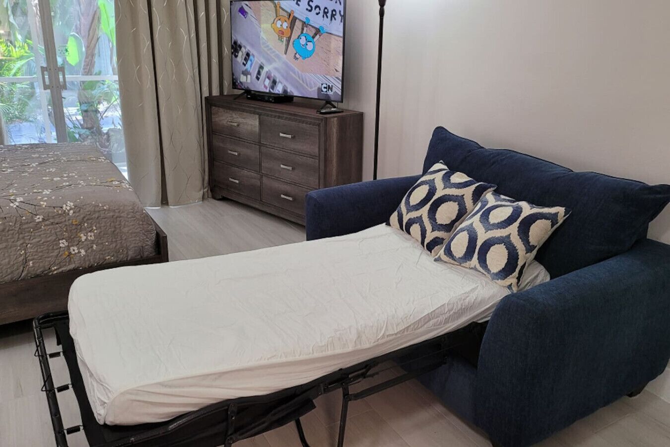 Una habitació amb un llit, un sofà, un televisor i una petita taula de nit.