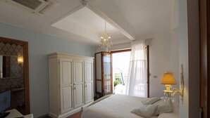 Une chambre à coucher comprenant un lit, un bureau, une armoire, un lustre et un téléphone.