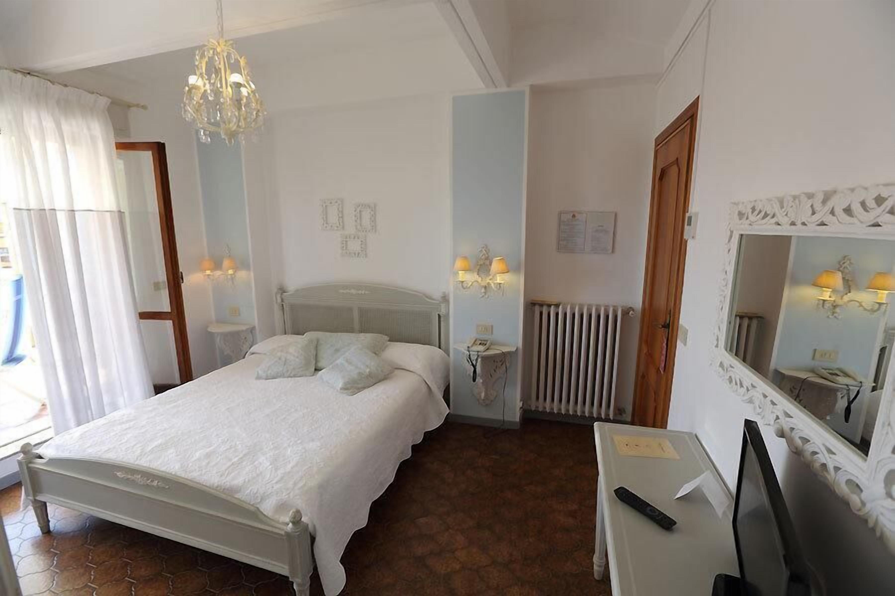 A bedroom with a bed, bedside table, TV, and a mirror.