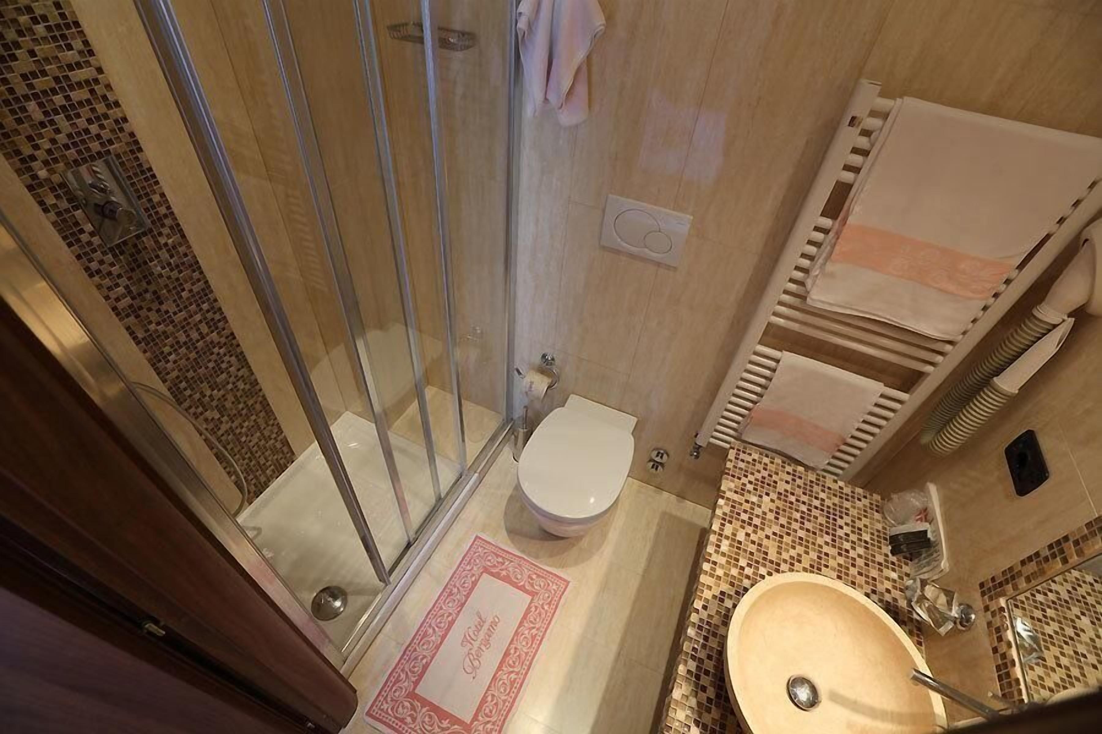 A bathroom with a glass-enclosed shower, a white toilet, and a sink with a mirror.