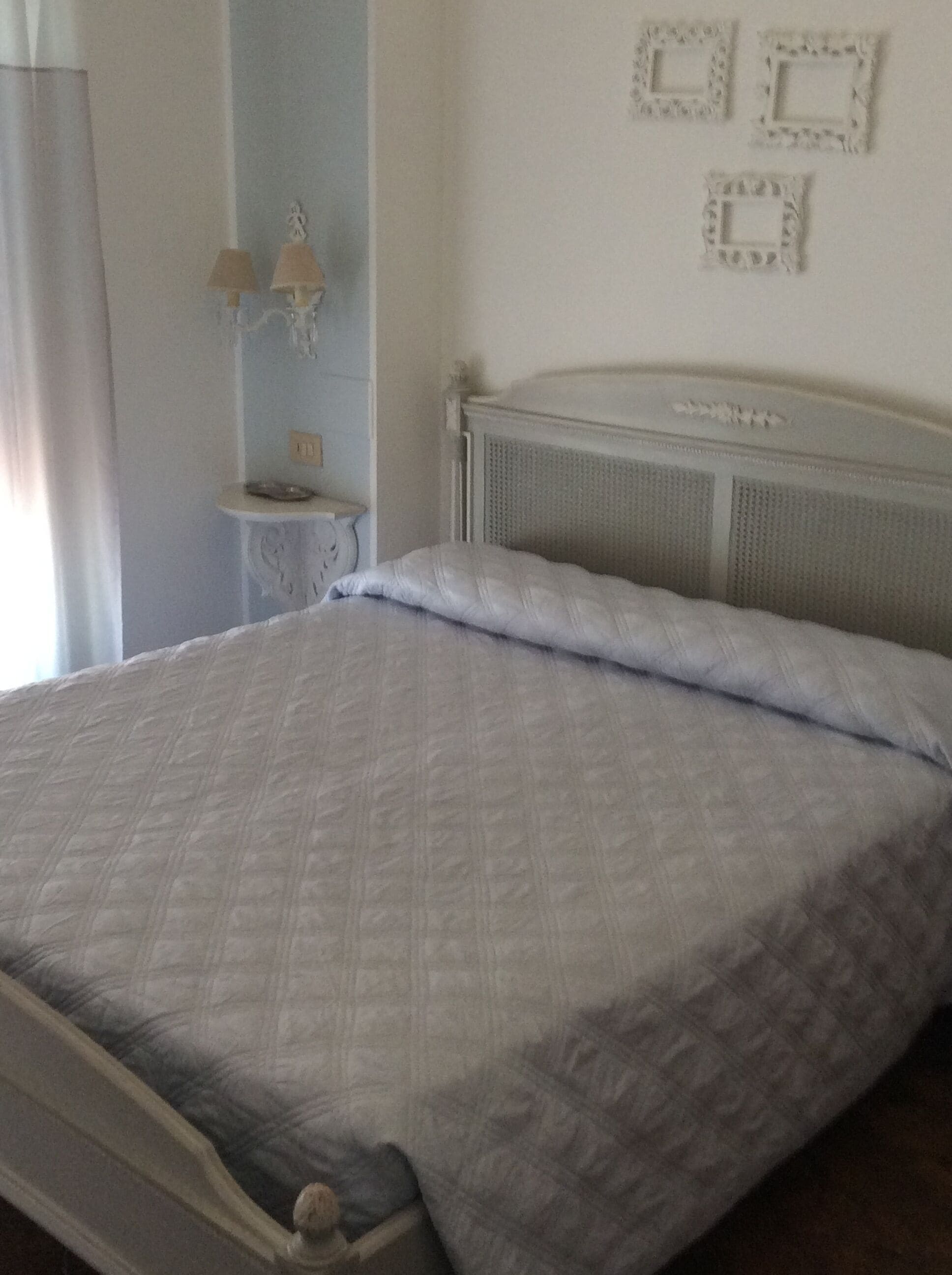 A bedroom with a bed, a nightstand, and a wall-mounted lamp.
