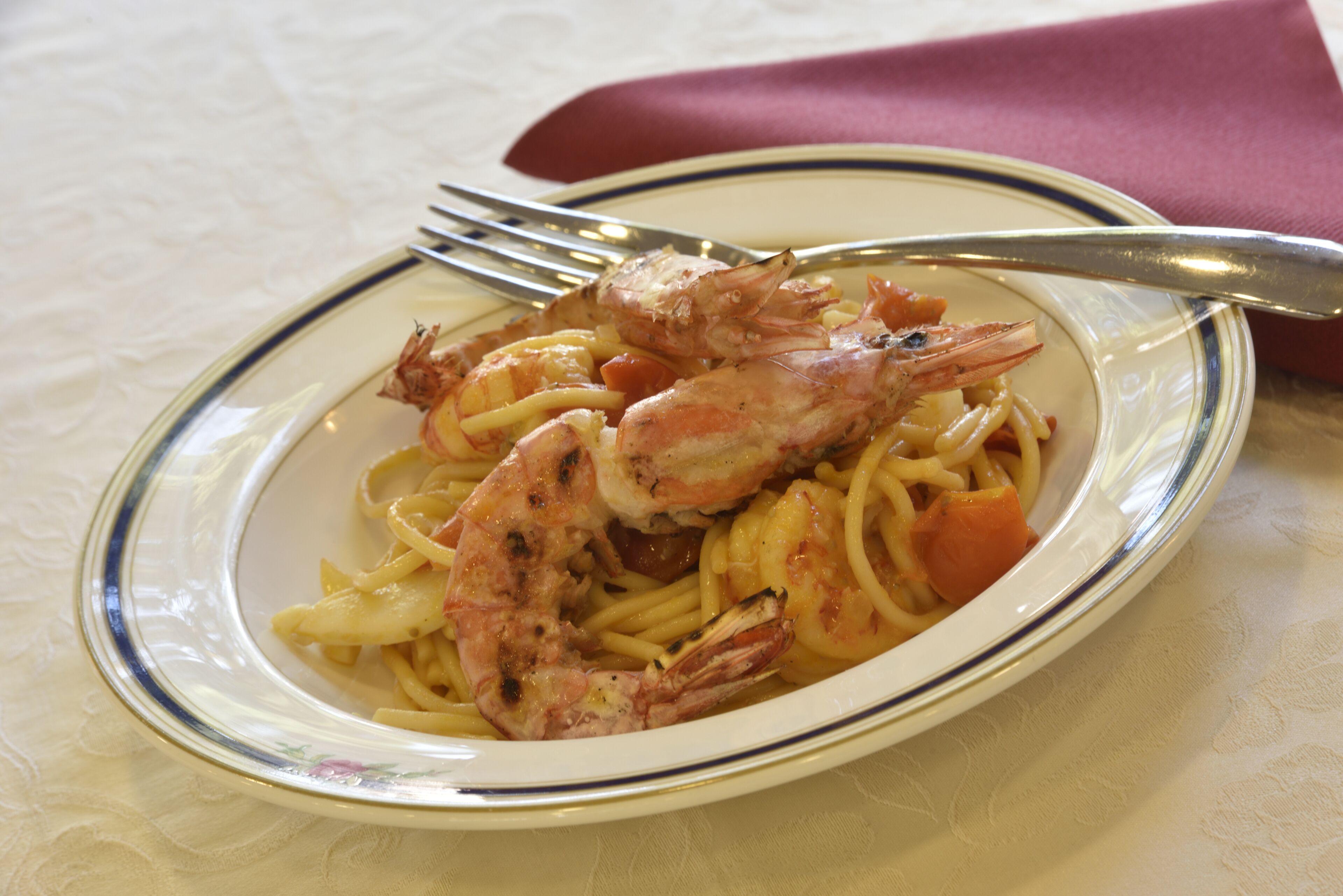 Une assiette de pâtes aux crevettes et à la sauce tomate.