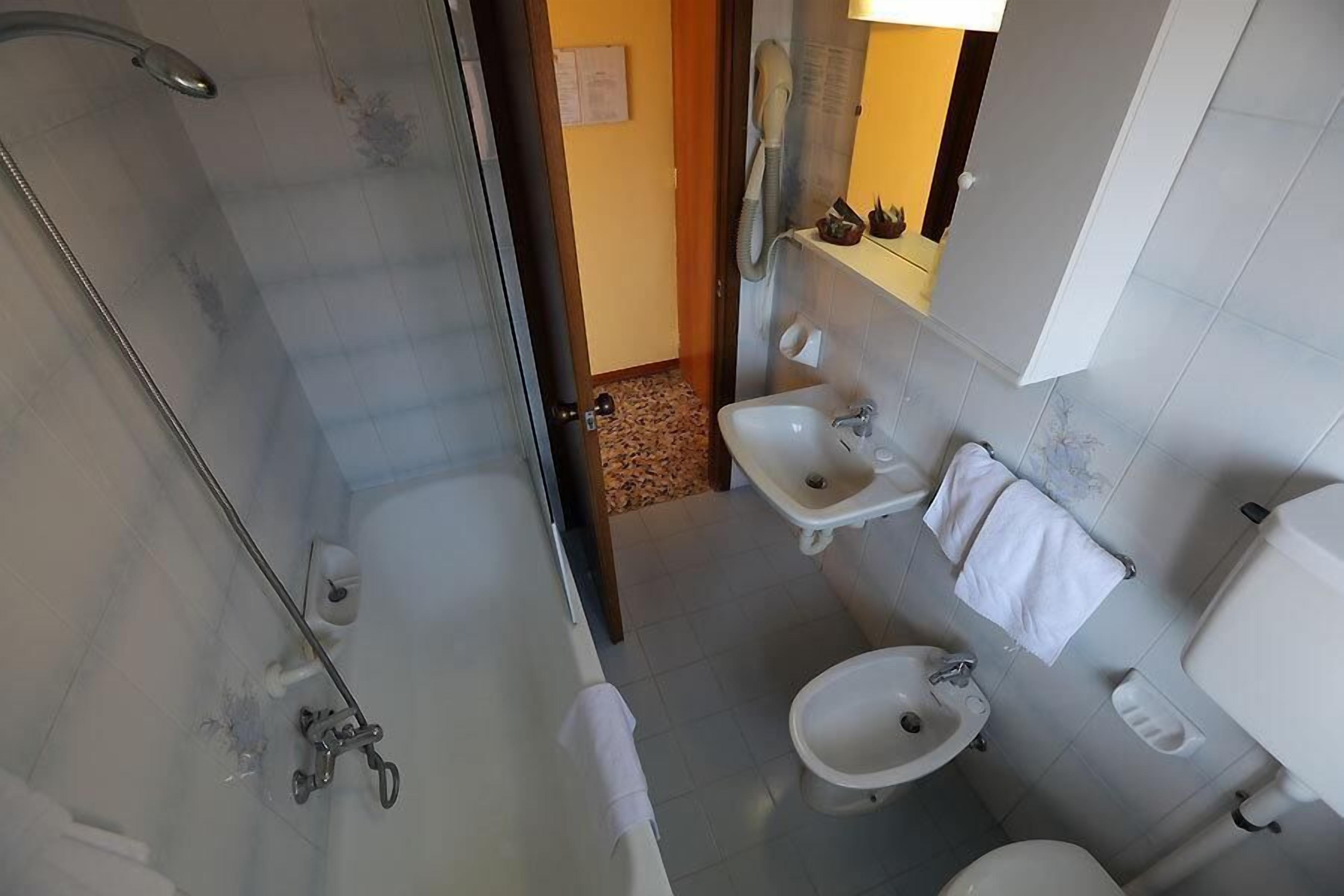 A bathroom with a glass-enclosed shower, a bathtub, a sink, and a toilet.