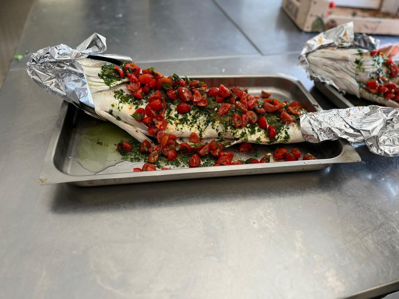 A fish wrapped in foil on a metal tray.