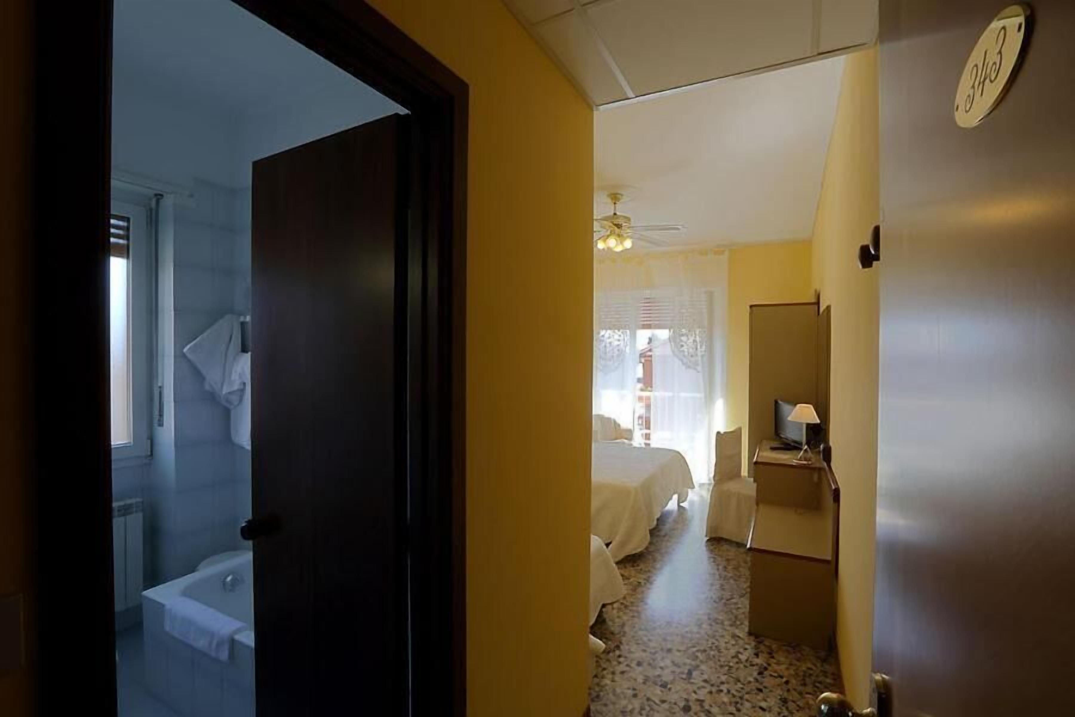 Une chambre d’hôtel avec une salle de bain, un lit, un bureau et une petite table.