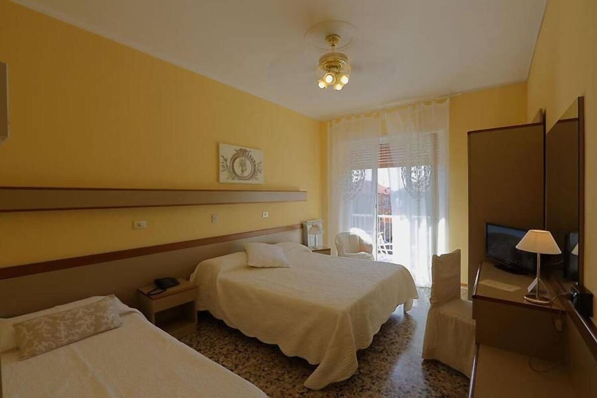Habitación de hotel con dos camas, un escritorio con televisor y una silla.