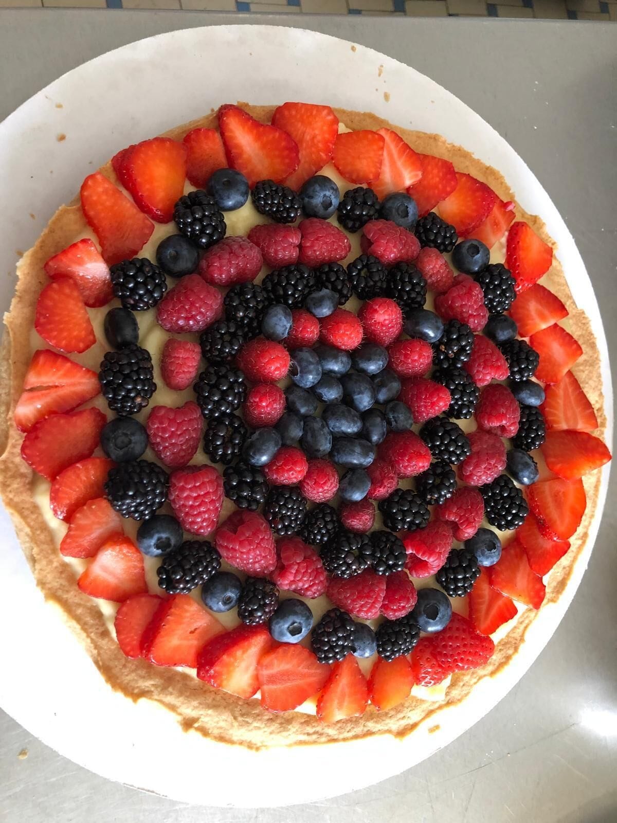 A round tart with a variety of fresh berries arranged in a circular pattern on top.