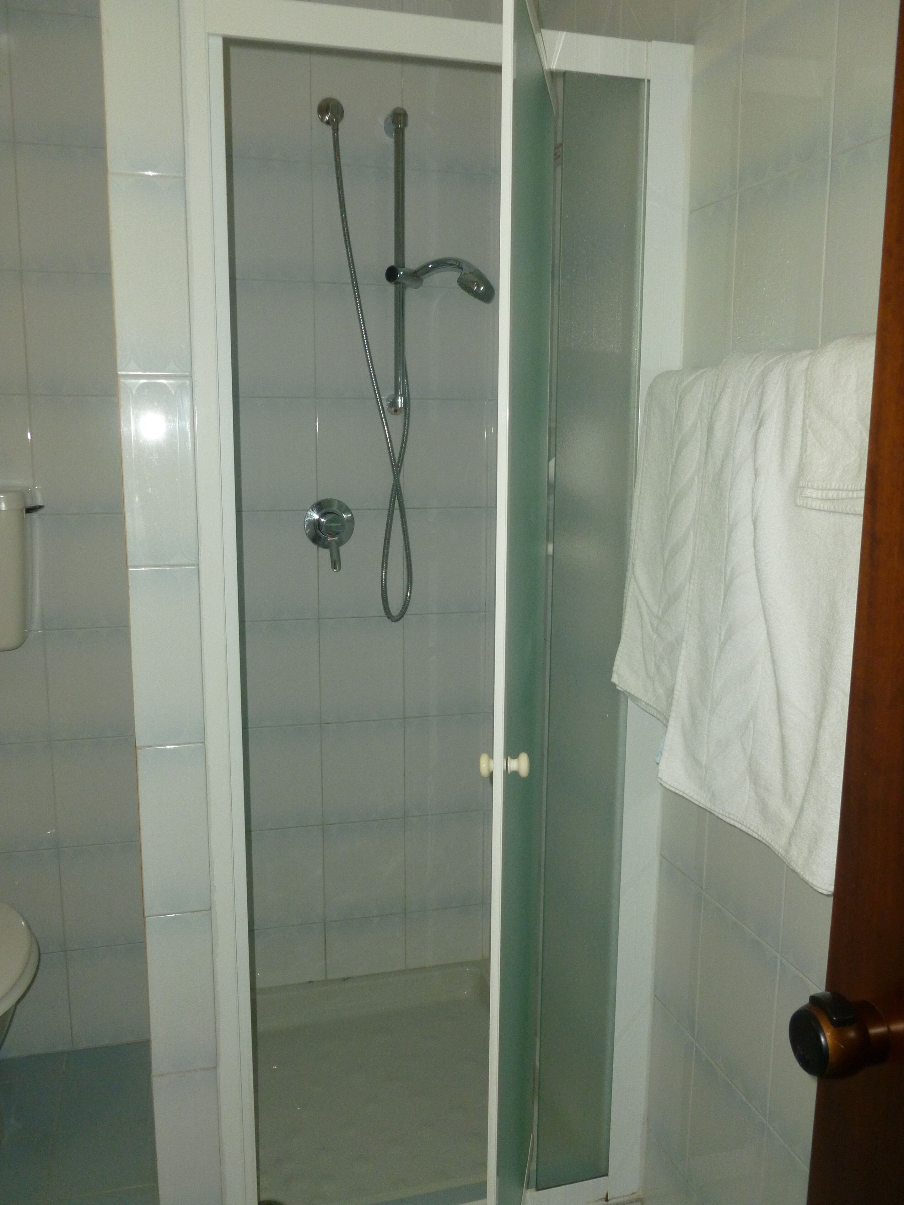 A glass-enclosed shower with a white towel hanging on the door.