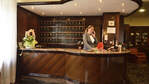 Un comptoir d’accueil avec un revêtement en bois, une plante en pot et un tableau encadré au mur.