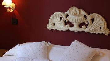 Camera d'albergo con parete rossa, un elemento decorativo a parete e un letto con cuscini e copripiumino bianchi.