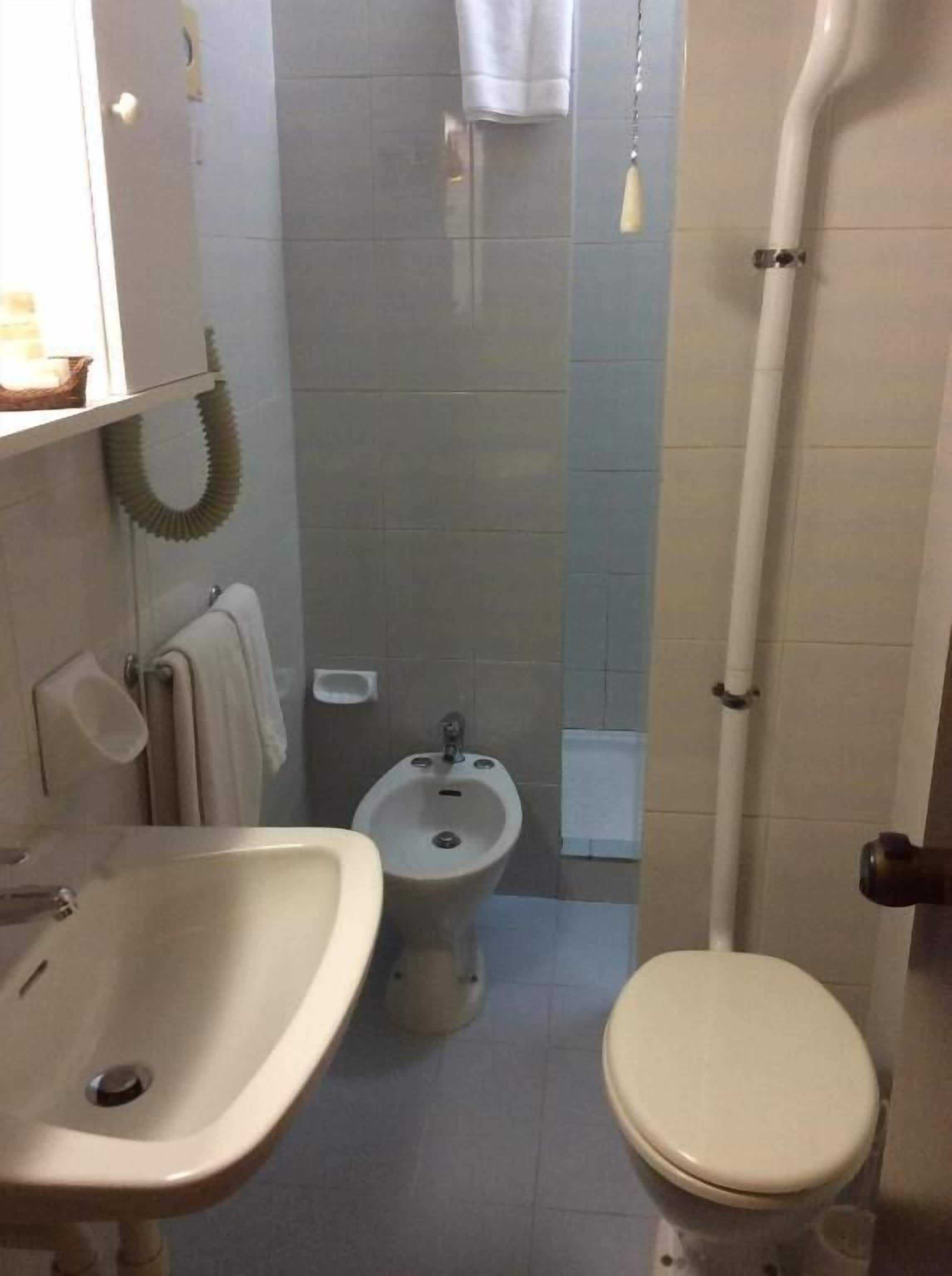 Um banheiro pequeno com pia, bidê e vaso sanitário.